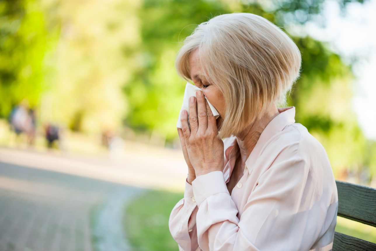 Senior woman blows her nose in attempt to receive springtime allergy relief.