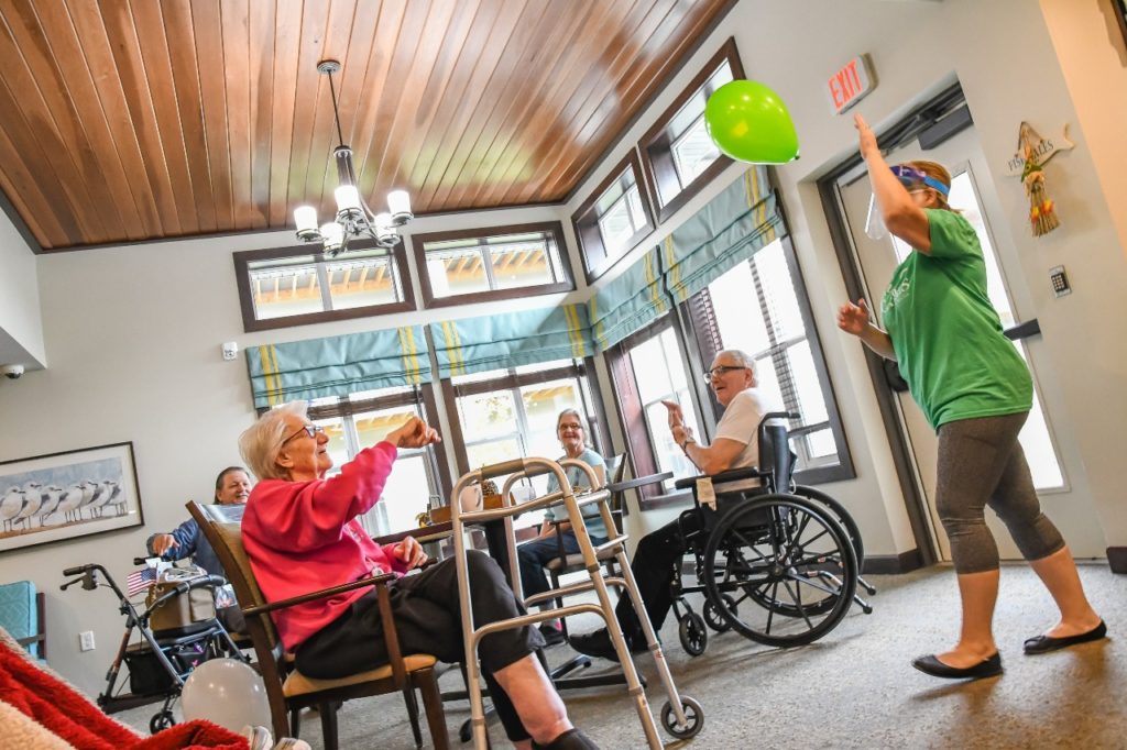 a person in a wheelchair holding a balloon in a room with people